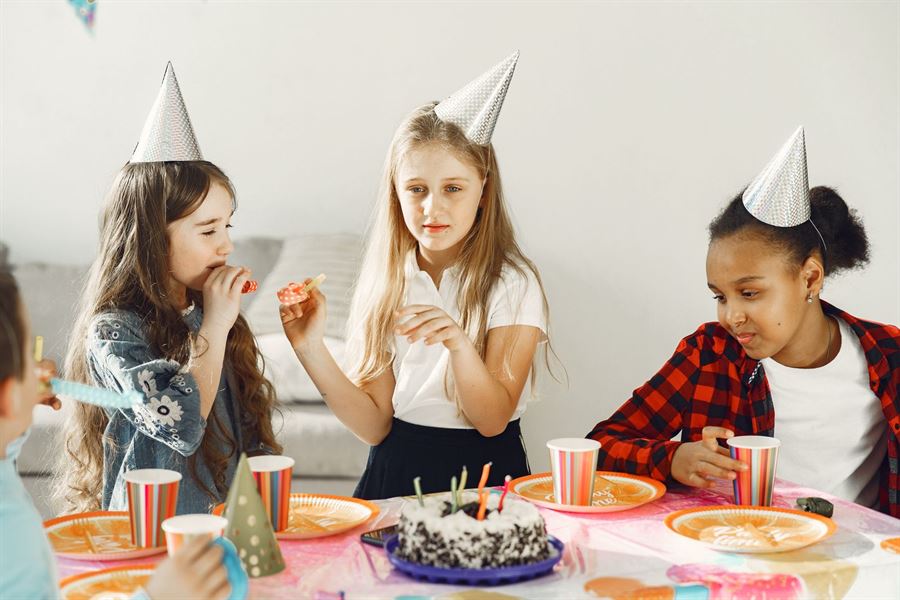 Chicas con gorritos de cumpleaños alrededor de la torta